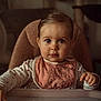 baby, child, high_chair, bib, pink, heart_pattern, long_sleeve, indoors, face, portrait, curious, cute, young_child, person, furniture, sitting, table, expression, soft_light, hair