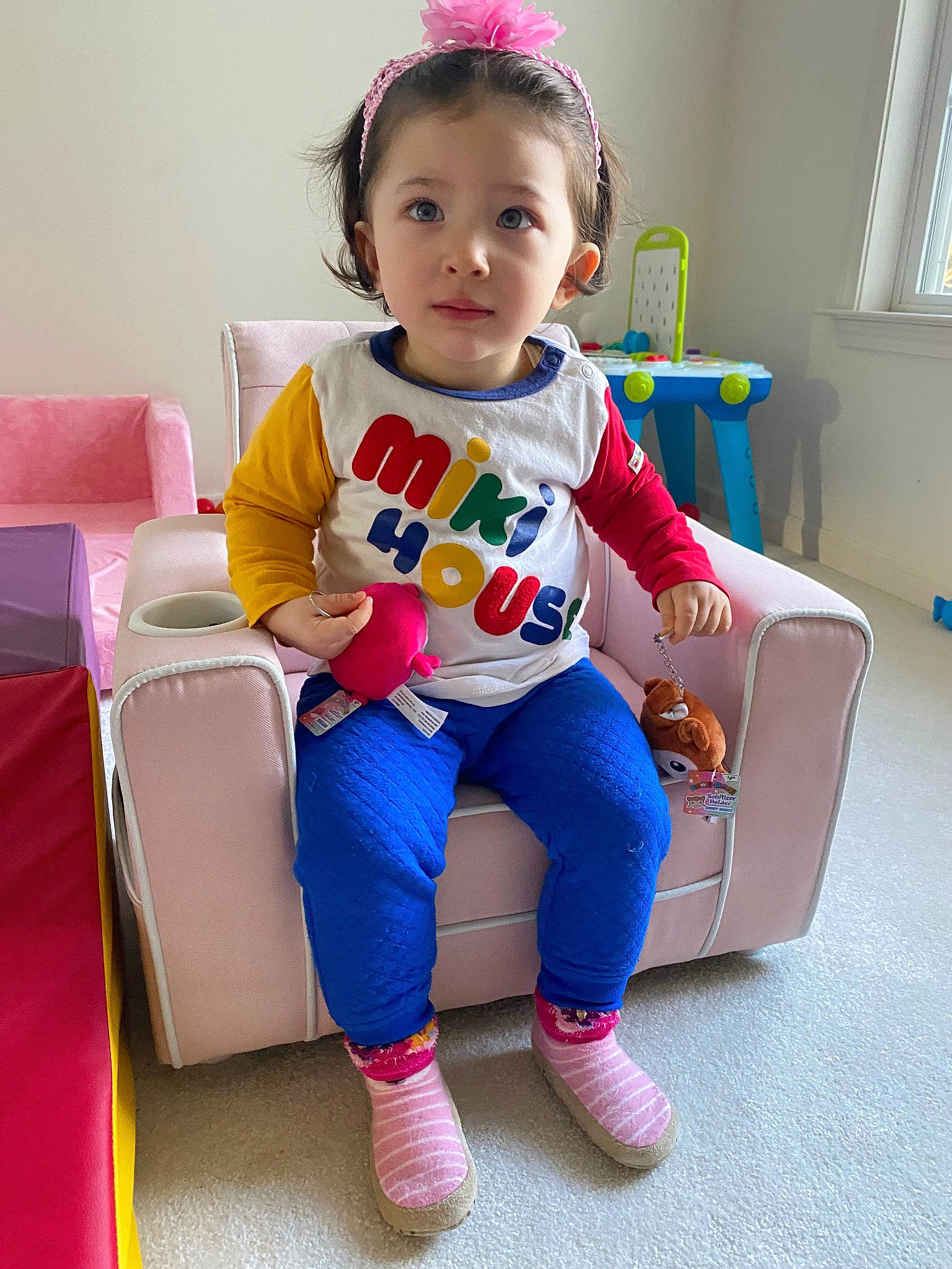 Lily is registered to the contest to win money with this photo: baby, baby_playing_with_toys, baby_toddler_clothing, child, clothing, curtain, electric_blue, fashion_accessory, happy, human_leg, magenta, person, play, sitting, sleeve, smile, sock, t_shirt, toddler, window