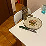 cat, tabby_cat, chair, table, plate, fork, knife, kitchen, tile_floor, white_wall, cutlery, glass, domestic_pet, indoor, furniture, animal, curious, sitting, waiting, home