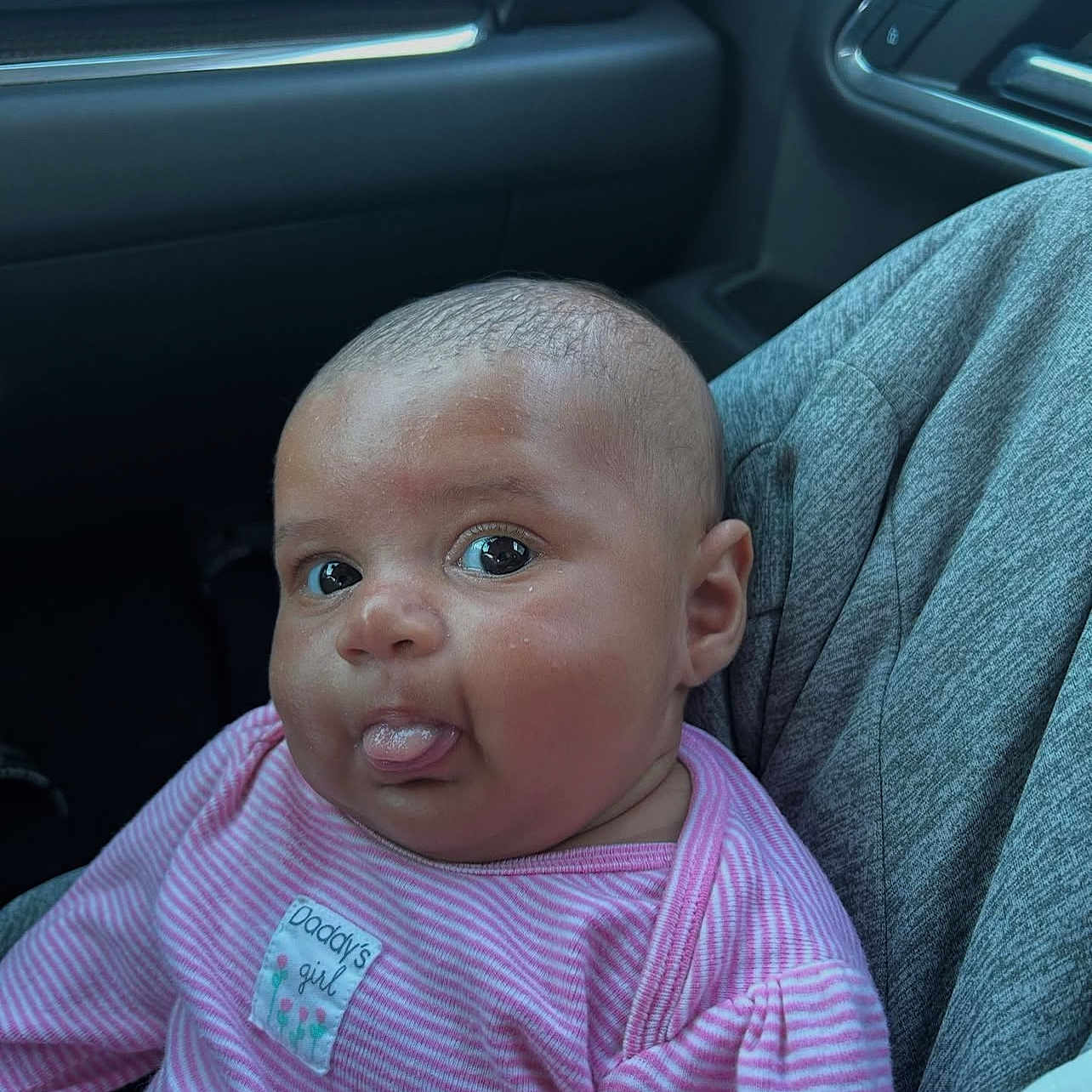 Savani joined the competition — help win amazing prizes! baby, car_interior, casual, child, cute, expression, eyes, face, head, human, infant, lap, person, pink_clothing, seat, sitting, skin, striped_shirt, tongue_out, young_child