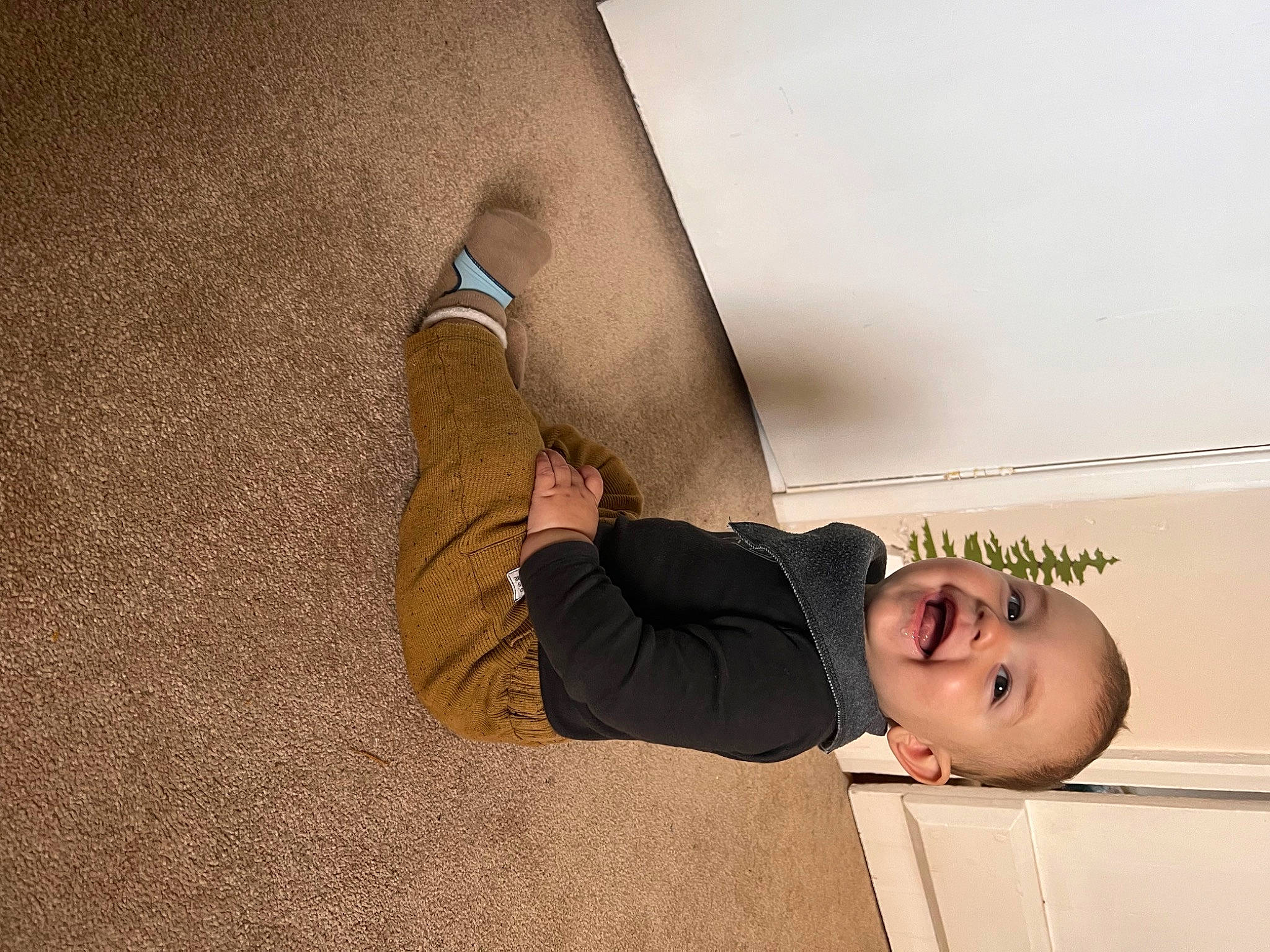 Harry is registered to the contest to win money with this photo: ceiling, comfort, elbow, floor, flooring, foot, gesture, happy, hardwood, human_leg, knee, person, room, shadow, shoulder, smile, thigh, toddler, wall, wood