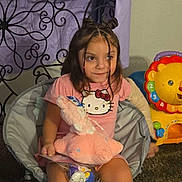 Millie joined the competition — help win amazing prizes! child, girl, braids, pink_shirt, hello_kitty, stuffed_animal, toy, chair, carpet, indoor, furniture, colorful_toy, lion_toy, playful, cute, smiling, hair_buns, childhood, room, relaxed