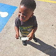 Maverick is registered to the contest to win money with this photo: black_shoes, boy, casual_clothing, child, concrete, daytime, happy, holding_money, outdoor, parking_lot, people, person, shadow, short_hair, smiling, standing, sunlight, tshirt, urban, young