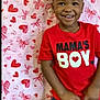 background_pattern, boy, child, clothing, cute, gap_tooth, hands, happy, hearts, indoors, looking_at_camera, love, party, portrait, red, red_shirt, short_hair, smiling, toddler, valentines_backdrop