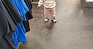 Miracle is registered to the contest to win money with this photo: bottle, casual_clothing, child, clothing_rack, clothing_store, curious, floor, flooring, hair_buns, indoor, pants, person, retail, shoes, shopping, sneakers, standing, sweatshirt, toddler, young_child