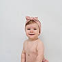 Lucie a rejoint le concours — aidez-le/la à gagner de superbes lots ! baby, child, smile, headband, bow, necklace, pink_clothing, diaper, sitting, fluffy_surface, cute, portrait, happy, infant, skin, bare_chest, white_background, studio, adorable, small_hands