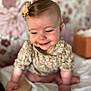 baby, child, smiling, hair_bow, floral_wallpaper, crawling, cute, indoors, soft_focus, skin, clothing, person, infant, happy, expression, portrait, young, background, room, toy