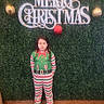 child, person, holiday, christmas, festive, greenery, background, sign, ornaments, onesie, striped_clothing, slippers, standing, indoor, portrait, decor, celebration, seasonal, expressionless, floor