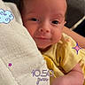 baby, blanket, cloud, cozy, cute, digital_stickers, expression, face, hand, heart, indoors, infant, newborn, person, portrait, relax, skin, star, timestamp, yellow_clothing