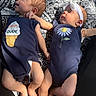 Amelia is registered to the contest to win money with this photo: baby, cute, face, flower_graphic, head, headband, holding_hands, ice_cream_graphic, indoors, infant, laying_down, natural_light, navy_blue_clothing, newborn, onesie, patterned_blanket, peaceful, skin, small_hands, two_babies