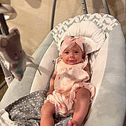 Amelia is registered to the contest to win money with this photo: baby, infant, pink_headband, baby_rocker, cushion, plush_toy, smiling, cute, indoors, child, clothing, fabric, blanket, foot, head, person, resting, soft_toys, baby_girl, comfort