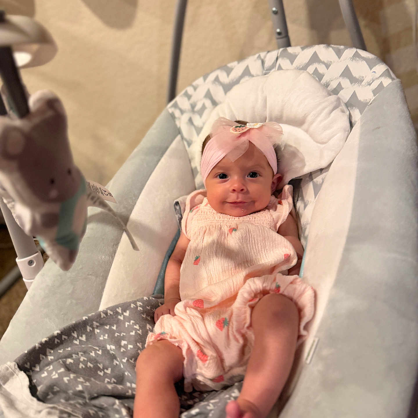 Amelia is registered to the contest to win money with this photo: baby, infant, pink_headband, baby_rocker, cushion, plush_toy, smiling, cute, indoors, child, clothing, fabric, blanket, foot, head, person, resting, soft_toys, baby_girl, comfort