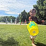child, toddler, grass, park, outdoor, sunny, bucket, yellow, octopus, barefoot, playing, summer, trees, people, daylight, casual_clothing, fun, kid, blue_sky, nature