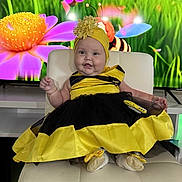 Valeria joined the competition — help win amazing prizes! baby, child, smiling, costume, dress, bee_costume, yellow, black, headwear, flower, cartoon, animated_background, chair, indoor, cute, happy, portrait, infant, footwear, celebration
