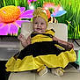 baby, child, smiling, costume, dress, bee_costume, yellow, black, headwear, flower, cartoon, animated_background, chair, indoor, cute, happy, portrait, infant, footwear, celebration