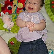 Aurora joined the competition — help win amazing prizes! baby, smiling, infant, child, clothing, play_mat, toy, colorful, happy, person, jeans, purple_shirt, hand_clasp, lying_down, indoor, cute, face, expression, playful, young