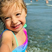 Saphia is registered to the contest to win money with this photo: child, smiling, girl, water, ocean, beach, swimsuit, rainbow_colors, happy, portrait, summer, sunlight, outdoor, playful, waves, skin, face, young, fun, vacation