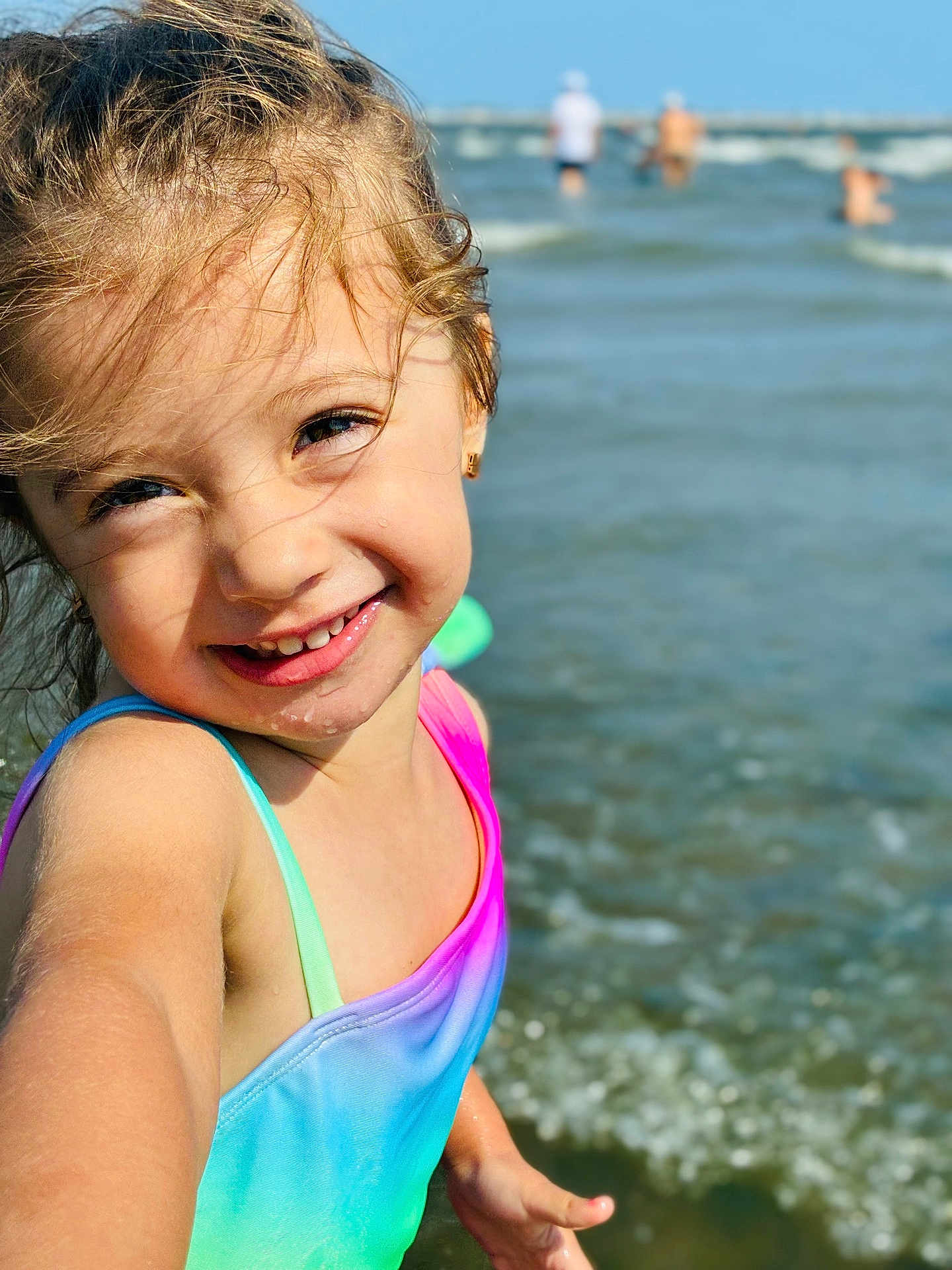 Saphia is registered to the contest to win money with this photo: child, smiling, girl, water, ocean, beach, swimsuit, rainbow_colors, happy, portrait, summer, sunlight, outdoor, playful, waves, skin, face, young, fun, vacation