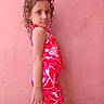 casual, child, colorful, colorful_clothing, confident, curly_hair, fashion, full_body, girl, outdoor, patterned_outfit, person, pink_wall, portrait, posing, side_view, standing, vibrant, wall, young