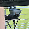 black_cat, cat, animal, pet, balcony, wooden_table, folding_table, gray_bucket, railing, outdoor, green_wall, relaxed, paw, fur, curious, domestic_cat, resting, daylight, window, home