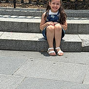 Sarah is registered to the contest to win money with this photo: child, girl, smile, sitting, steps, outdoor, sunlight, happy, braided_hair, dress, sandals, stone, pavement, fence, nature, daytime, casual, portrait, person, urban