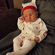 Myla joined the competition — help win amazing prizes! baby, infant, onesie, hat, cherry_pattern, blanket, cushion, resting, indoors, cute, child, sleepwear, headwear, person, portrait, cozy, soft_lighting, seated, small_hands, footed_pajamas