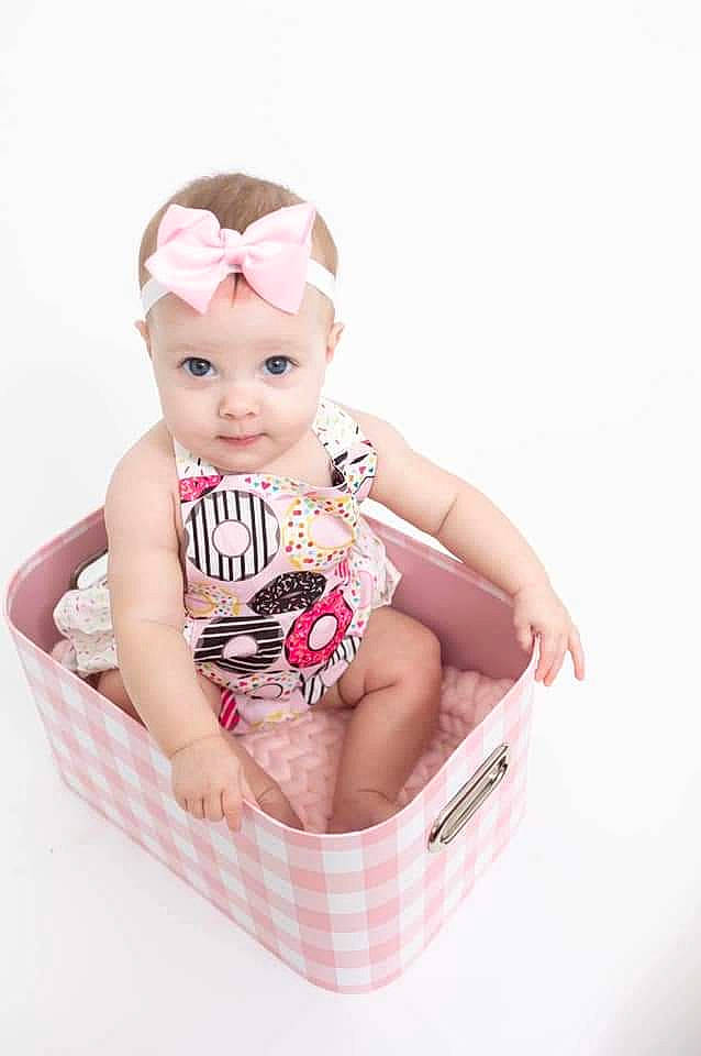Kinsleigh is registered to the contest to win money with this photo: baby, baby_products, baby_safety, baby_toddler_clothing, basket, cheek, child, facial_expression, fashion_accessory, foot, hair_accessory, happy, head, headwear, pattern, person, portrait_photography, sitting, skin, sleeve