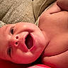 baby, infant, smiling, face, skin, mouth, eyes, couch, cushion, texture, happy, lying_down, closeup, indoors, child, person, expression, warm_lighting, portrait, bare_skin