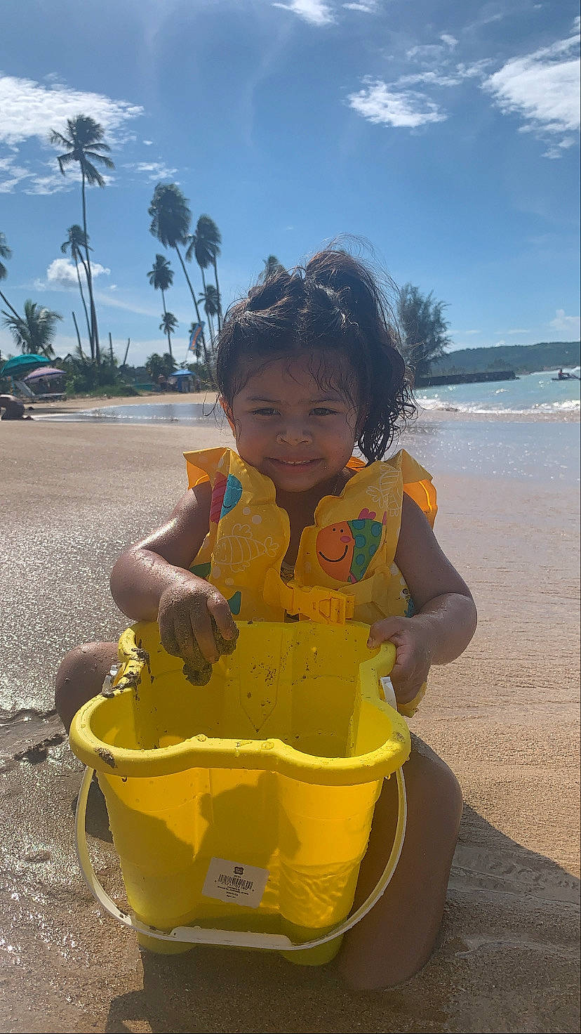 Alianna is registered to the contest to win money with this photo: baby, beach, cloud, coast, fun, happy, joy, leisure, palm_tree, people_in_nature, person, play, recreation, sand, sitting, sky, soil, toddler, tourism, travel