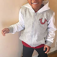 Logan joined the competition — help win amazing prizes! child, smiling, hoodie, casual_clothing, sneakers, standing, indoor, person, young, happy, black_pants, floor, wall, earring, fashion, feet, full_body, portrait, wooden_floor, light