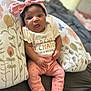 Genesis joined the competition — help win amazing prizes! baby, infant, pink_bow, headband, pants, white_socks, floral_cushion, shirt, text_on_shirt, tongue_out, cute, indoor, bed, blanket, person, smiling, seated, soft_lighting, closeup, portrait