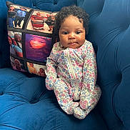 Genesis is registered to the contest to win money with this photo: baby, child, onesie, floral_pattern, couch, blue_couch, pillow, photo_collage, indoor, cute, infant, seated, curly_hair, face, portrait, soft_furniture, comfortable, family_photos, home, young_child