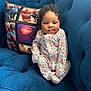 baby, child, onesie, floral_pattern, couch, blue_couch, pillow, photo_collage, indoor, cute, infant, seated, curly_hair, face, portrait, soft_furniture, comfortable, family_photos, home, young_child