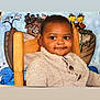 birds, boat, cartoon_animals, child, colorful_mural, cozy, cute, face, giraffes, happy, indoor, knitted_sweater, person, portrait, rabbits, seated, smiling, toddler, wooden_chair, young_child