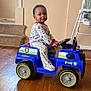 Gaberial is registered to the contest to win money with this photo: baby, blue, child, cute, floor, happy, home, indoor, pajamas, person, play, police_car, seat, smiling, stairs, steering_wheel, toddler, toy_car, vehicle, wooden_floor