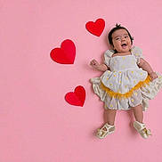 Diana joined the competition — help win amazing prizes! baby, child, smiling, dress, white_dress, yellow, hearts, pink_background, lying_down, happy, cute, footwear, shoes, celebration, adorable, infant, portrait, studio_photo, colorful, playful