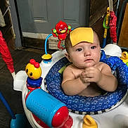 Oakes is registered to the contest to win money with this photo: baby, child, cheese, activity_center, toy, indoor, face, expression, hands, seat, colorful, play, curious, infant, blue, red, yellow, plastic, furniture, wood