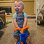 Rowan joined the competition — help win amazing prizes! toddler, child, indoor, toy_bike, pacifier, carpet, living_room, fireplace, family_photos, clock, cat_tree, blue, orange, overalls, short_sleeve, smiling, barefoot, furniture, home, playtime