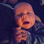 Ryker is registered to the contest to win money with this photo: baby, infant, hands, clasped_hands, sleepy, face, person, dim_lighting, blur, noise, indoor, clothing, long_sleeve, closeup, head, skin, expression, young_child, portrait, candid