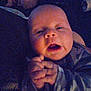 baby, infant, hands, clasped_hands, sleepy, face, person, dim_lighting, blur, noise, indoor, clothing, long_sleeve, closeup, head, skin, expression, young_child, portrait, candid