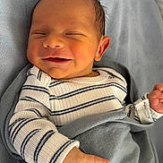 Enzo is registered to the contest to win money with this photo: baby, newborn, infant, smile, face, hand, blanket, striped_clothing, cozy, cute, sleepy, person, portrait, soft, closeup, indoors, skin, head, happy, resting
