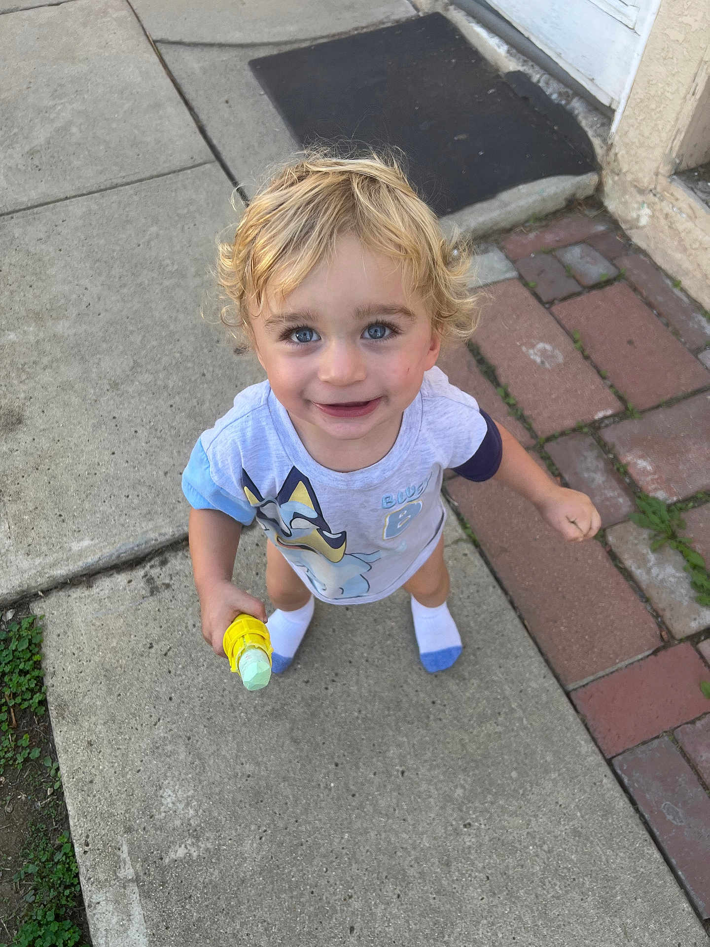 Atom joined the competition — help win amazing prizes! toddler, child, blonde_hair, blue_eyes, smiling, outdoor, sidewalk, chalk, toy, socks, short_sleeve_shirt, curly_hair, happy, person, concrete, brick_path, door_mat, playful, daylight, casual_clothing