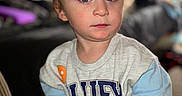 Atom is registered to the contest to win money with this photo: blond_hair, blue_eyes, cartoon_characters, casual_clothing, child, couch, curious_expression, cute, eyebrows, face, focused, hand_position, indoor, long_sleeve_shirt, person, portrait, seated, soft_background, toddler, young_child