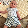 baby, infant, child, onesie, shorts, plaid, quilted_mat, carpet, toy, animal_print, cute, lying_down, indoor, soft_texture, playtime, curious, person, skin, face, legs