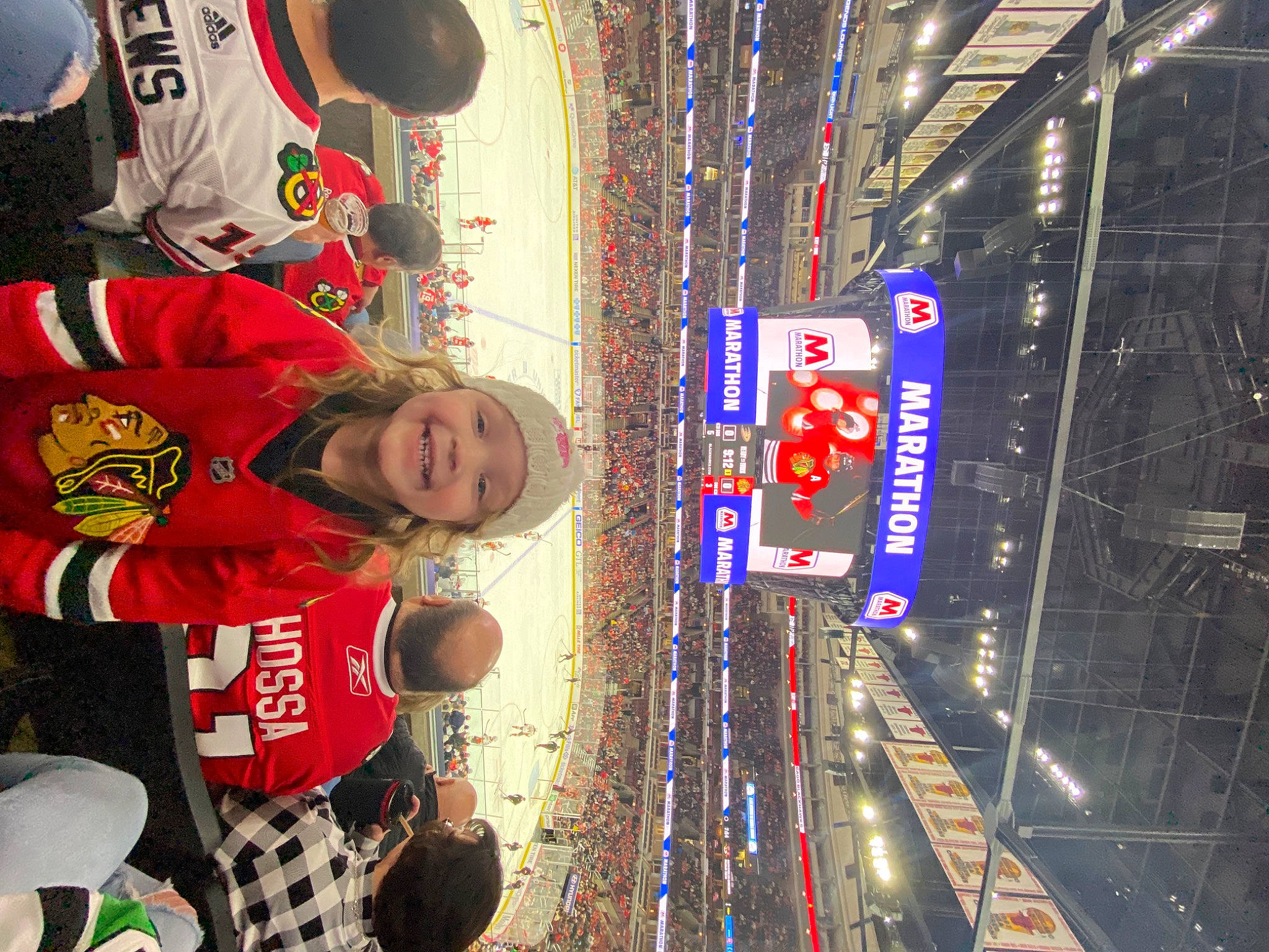 Kelsey is registered to the contest to win money with this photo: advertising, building, city, electric_blue, electricity, electronic_signage, event, fan, fun, headwear, jersey, joy, leisure, logo, pedestrian, person, recreation, smile, sportswear, t_shirt