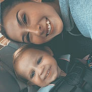 Remington is registered to the contest to win money with this photo: woman, toddler, car_seat, smile, happy, child, person, safety_harness, seatbelt, braid, casual_clothing, indoor, closeup, portrait, family, car_interior, child_safety, bonding, joy, transportation