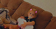 Remington is registered to the contest to win money with this photo: baby, child, couch, sofa, pacifier, toy, butterfly_toy, blanket, pillow, indoor, living_room, infant, sitting, clothing, face, feet, cute, digital_filter, pink_horns, relaxing