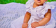 Elaya joined the competition — help win amazing prizes! baby, child, infant, white_dress, blanket, outdoor, grass, curly_hair, sitting, portrait, cute, skin, feet, hands, young, person, nature, daylight, expression, innocence