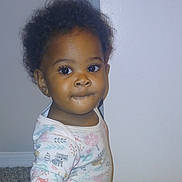Elaya is registered to the contest to win money with this photo: toddler, child, baby, onesie, indoor, carpet, curly_hair, face, person, cute, expression, sitting, animal_print, long_sleeve, infant, portrait, young_child, looking, floor, wall