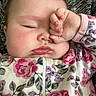Aurelia is registered to the contest to win money with this photo: baby, sleepy, hand, face, floral_clothing, onesie, chubby_cheeks, infant, portrait, close_up, cute, child, skin, pink, texture, person, resting, indoors, toddler, young